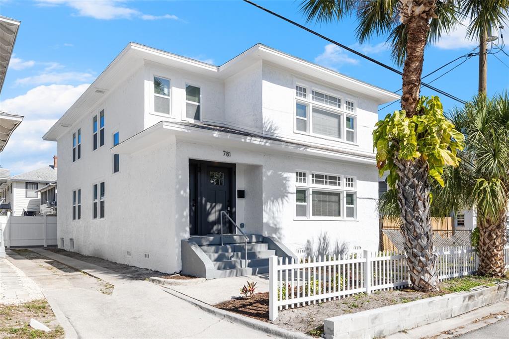 A two-story white stucco house features a dark front door and a white picket fence — 781 31ST AVENUE N, ST PETERSBURG, FL