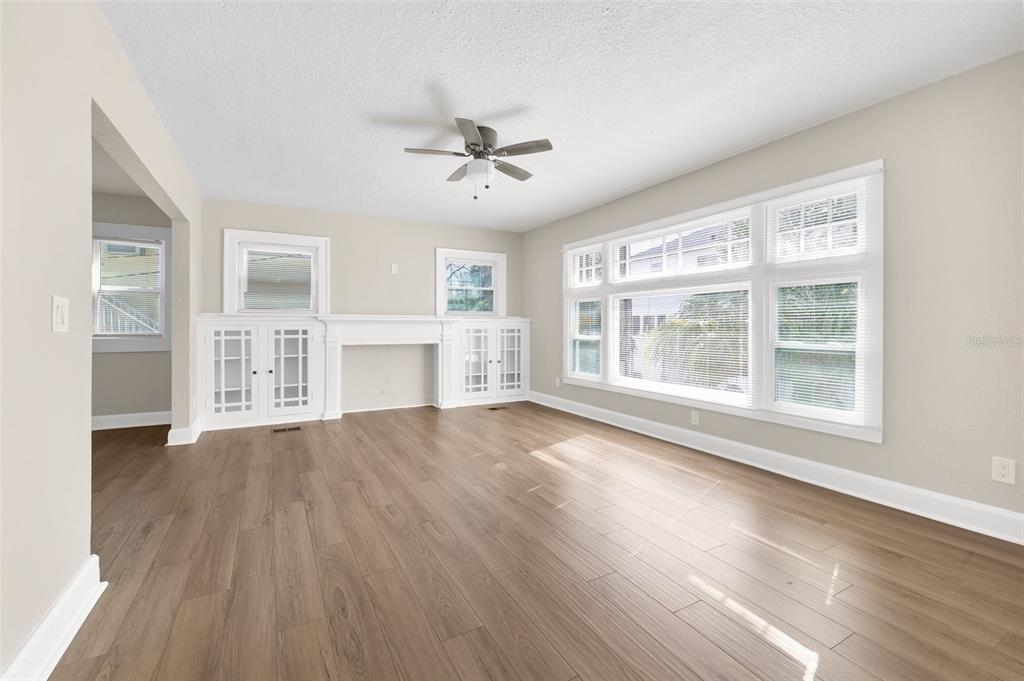 A living room with light wood flooring, a white fireplace, built-in cabinets, and large windows — 781 31ST AVENUE N, ST PETERSBURG, FL
