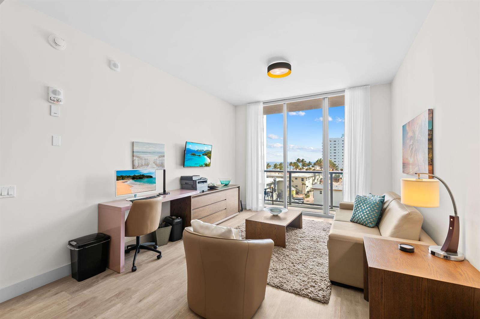 A living room with a desk, sofa, armchair, and a balcony overlooking the ocean — 777 N Ocean Drive # N407, Hollywood FL 33019, HOLLYWOOD, FL