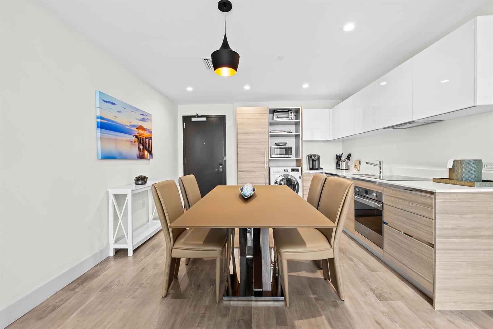 A modern kitchen and dining area features a light wood table, beige chairs, and white cabinetry — 777 N Ocean Drive # N407, Hollywood FL 33019, HOLLYWOOD, FL