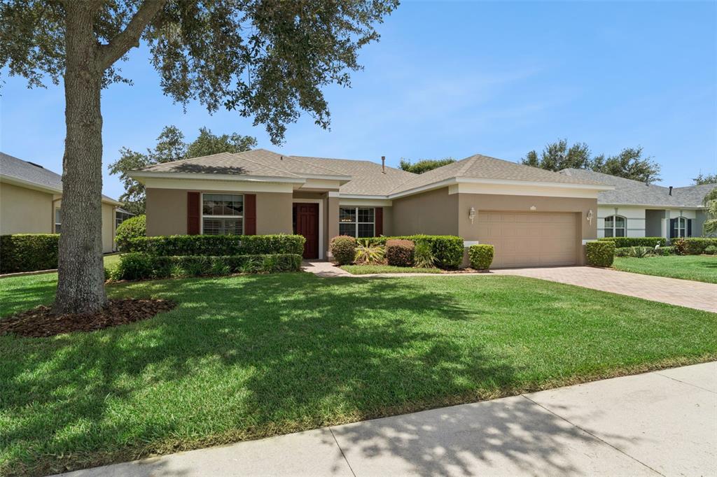 A single-story house with a tan exterior, a two-car garage, and a manicured front lawn — 1028 EVEREST STREET, CLERMONT, FL