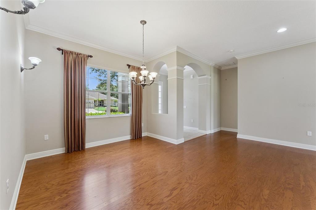A dining room with hardwood floors, a chandelier, and arched openings leading to another room — 1028 EVEREST STREET, CLERMONT, FL