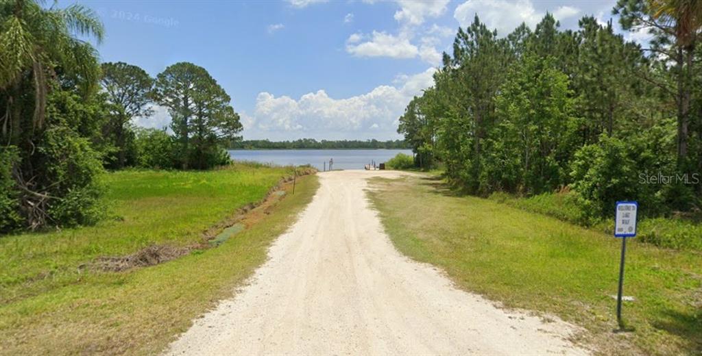 A dirt road leads to a boat ramp on a lake surrounded by trees — 1302 LAKESIDE DRIVE S, SEBRING, FL