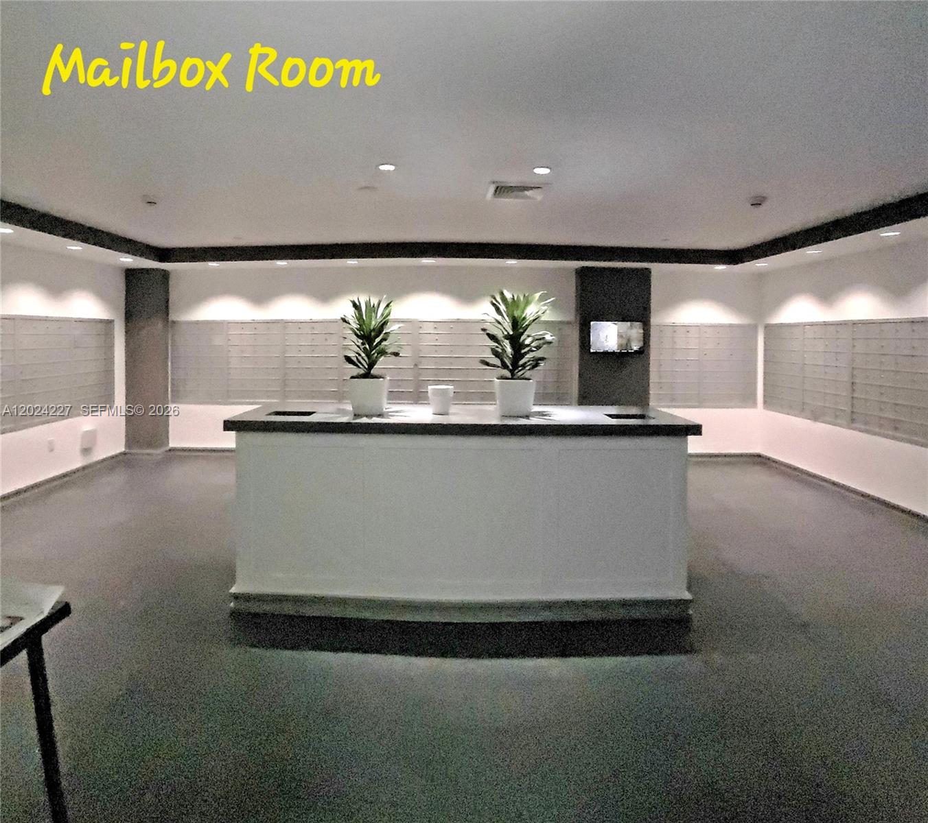 This mailbox room features a central counter with two potted plants and wall-mounted mailboxes — 90 SW 3rd St # 2208, Miami FL 33130, MIAMI, FL