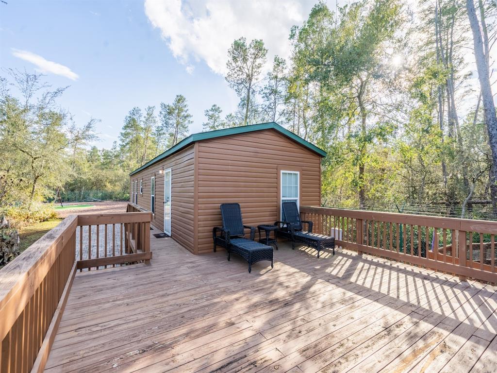 A wooden cabin features a large deck with two lounge chairs and a railing — 5600 NE NFR 5, SILVER SPRINGS, FL