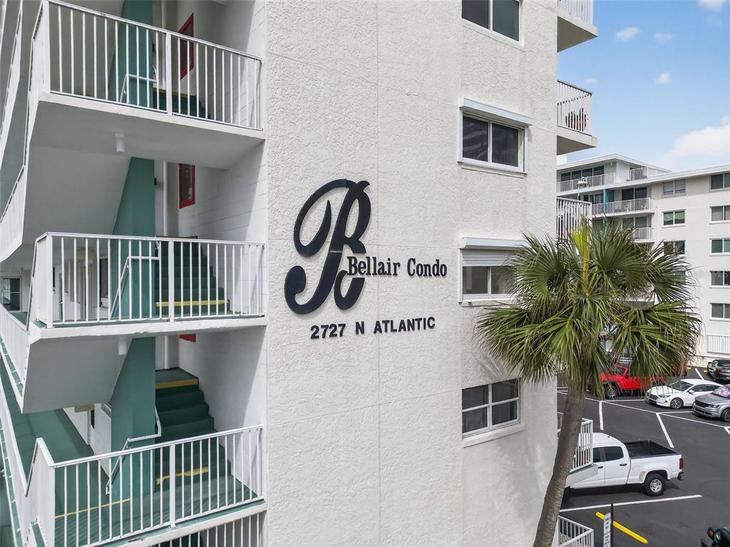 An exterior view of a white multi-story condo building with an outdoor staircase and palm tree — 2727 N ATLANTIC AVENUE UNIT 3170, DAYTONA BEACH, FL