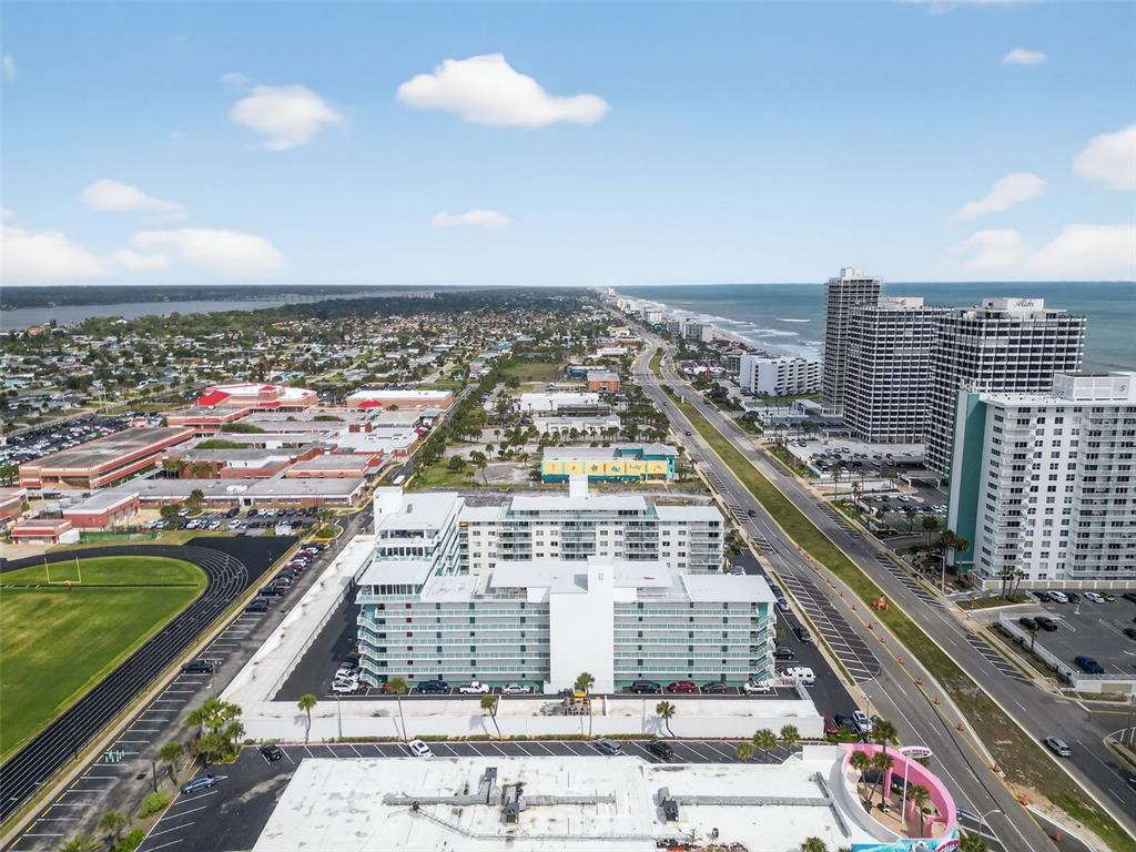 An aerial view shows a multi-story apartment complex near a beach and coastal highway — 2727 N ATLANTIC AVENUE UNIT 3170, DAYTONA BEACH, FL