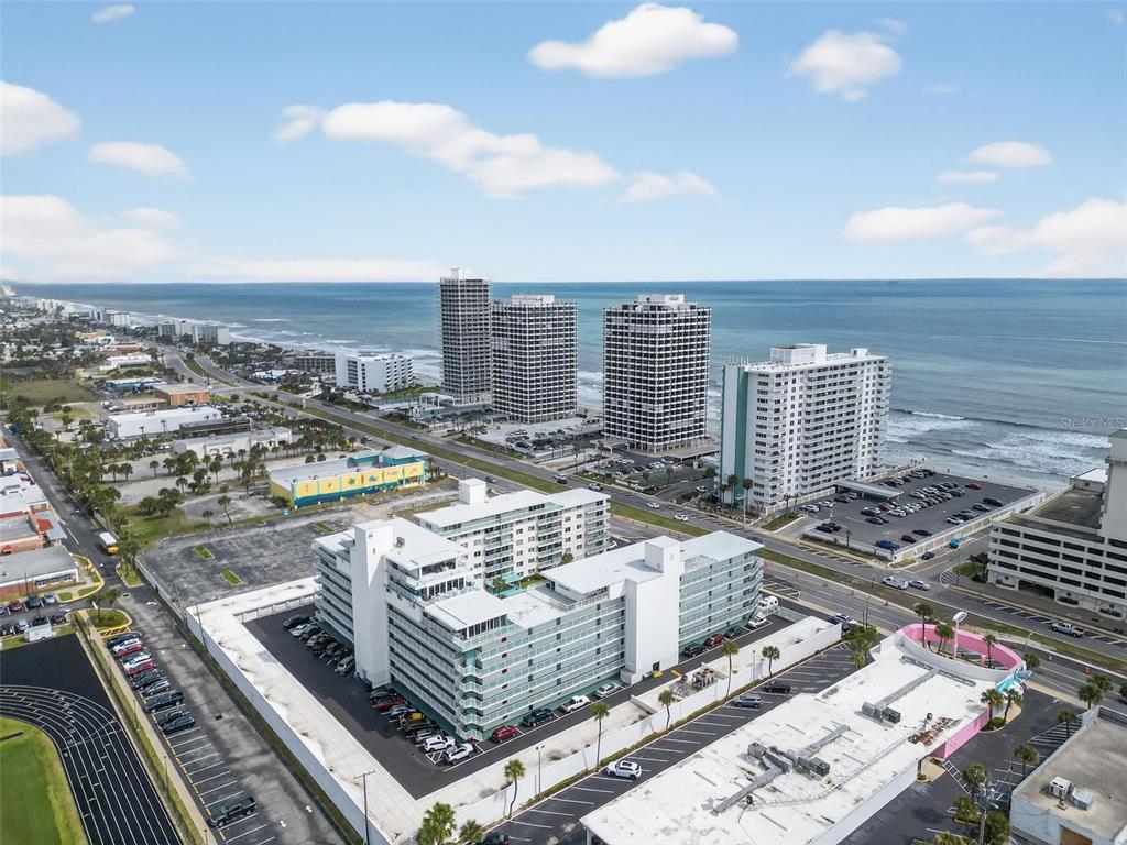 An aerial view shows a white multi-story apartment complex near a beach and ocean — 2727 N ATLANTIC AVENUE UNIT 3170, DAYTONA BEACH, FL