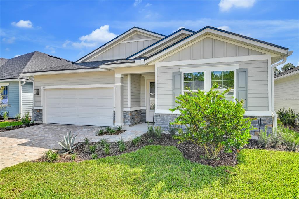 A single-story house with light gray siding, a stone facade, and a paved driveway — 219 THORNBERRY WAY, PALM COAST, FL