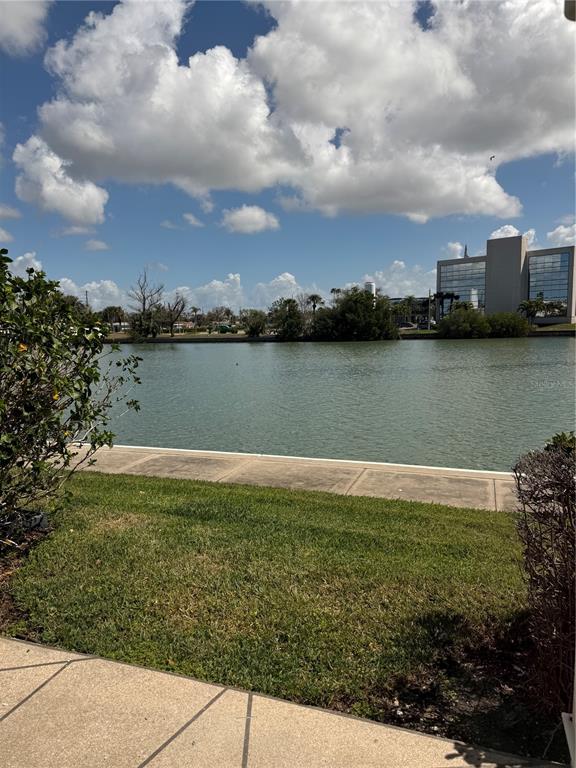 A view of a lake from a patio with a grassy lawn and nearby buildings — 7425 BAY ISLAND DRIVE S UNIT 103, SOUTH PASADENA, FL
