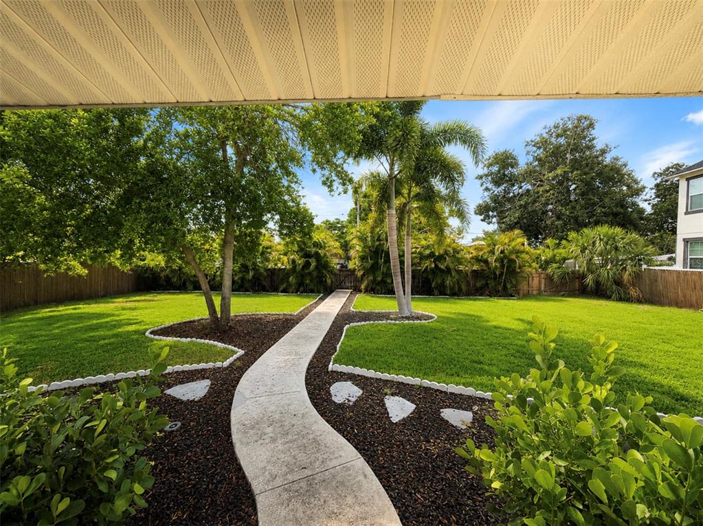 A backyard with a grassy lawn, palm trees, and a patio attached to a house — 940 25TH STREET N, ST PETERSBURG, FL