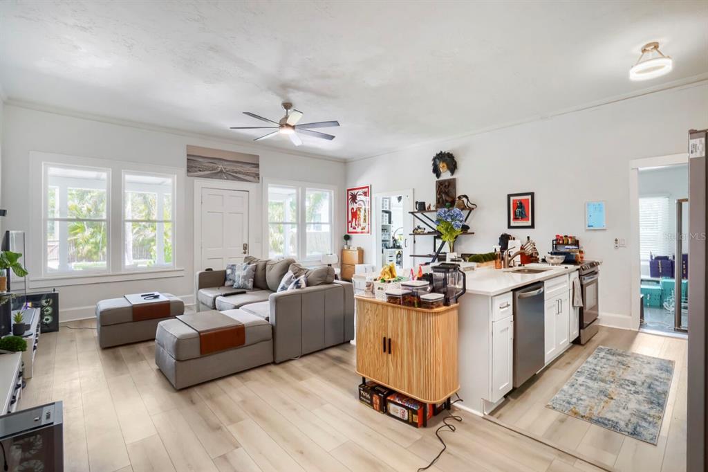 An open-concept living room and kitchen featuring light wood flooring, a gray sectional, and island — 940 25TH STREET N, ST PETERSBURG, FL