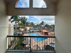 A view from a balcony overlooking a swimming pool, palm trees, and a parking lot — 6292 NW 186th St # 306, Hialeah FL 33015, HIALEAH, FL