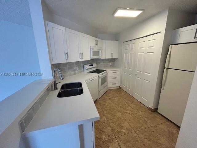 A kitchen features white cabinets, a double sink, stainless steel appliances, and tile flooring — 6292 NW 186th St # 306, Hialeah FL 33015, HIALEAH, FL