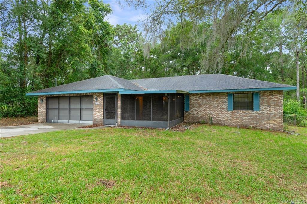 A single-story brick house features a two-car garage and a screened-in front porch — 3754 S APOPKA AVENUE, INVERNESS, FL