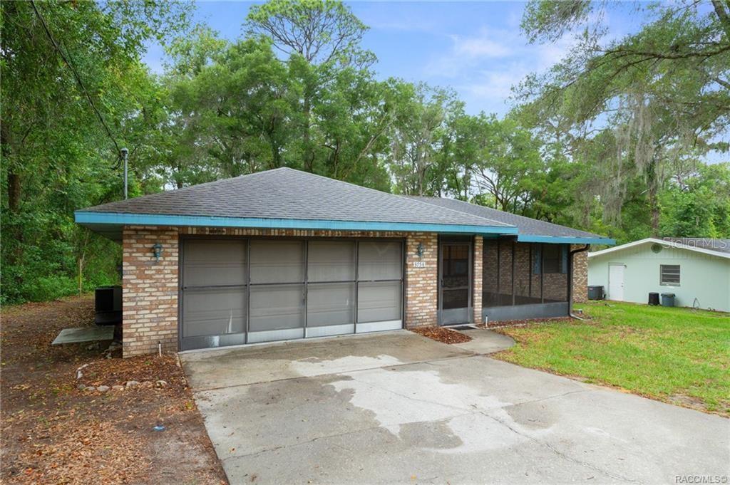 A single-story brick house features a screened-in garage and a front porch — 3754 S APOPKA AVENUE, INVERNESS, FL