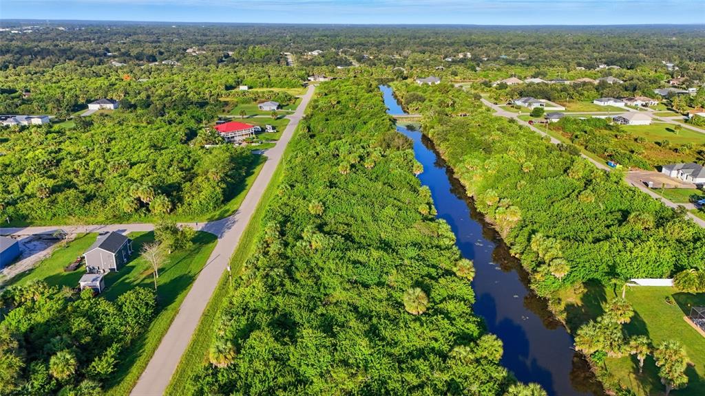 An aerial view shows a canal running through a wooded area next to a road — 346 RUTLAND CIRCLE, PORT CHARLOTTE, FL