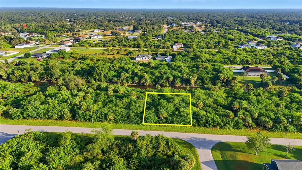 An aerial view shows a vacant, wooded lot outlined in yellow along a paved road — 346 RUTLAND CIRCLE, PORT CHARLOTTE, FL