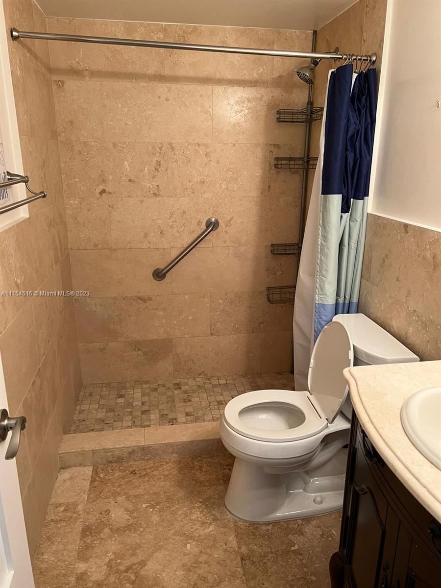 A bathroom features a walk-in shower with beige tile, a grab bar, and a toilet — 3725 S Ocean Dr # 301, Hollywood FL 33019, HOLLYWOOD, FL