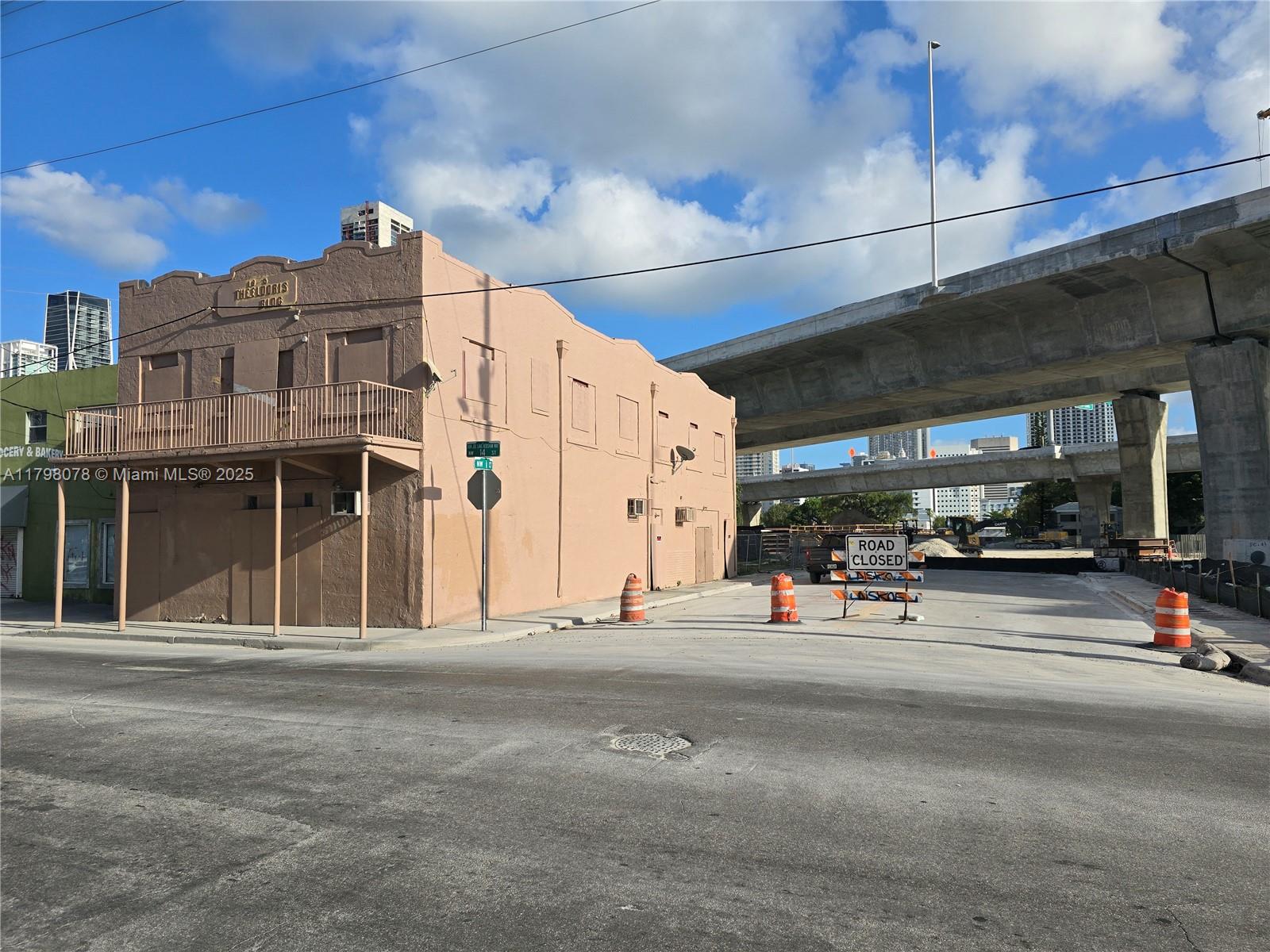 A tan, two-story building stands at a street corner near an elevated highway overpass — 130 NW 14th St, Miami FL 33136, MIAMI, FL
