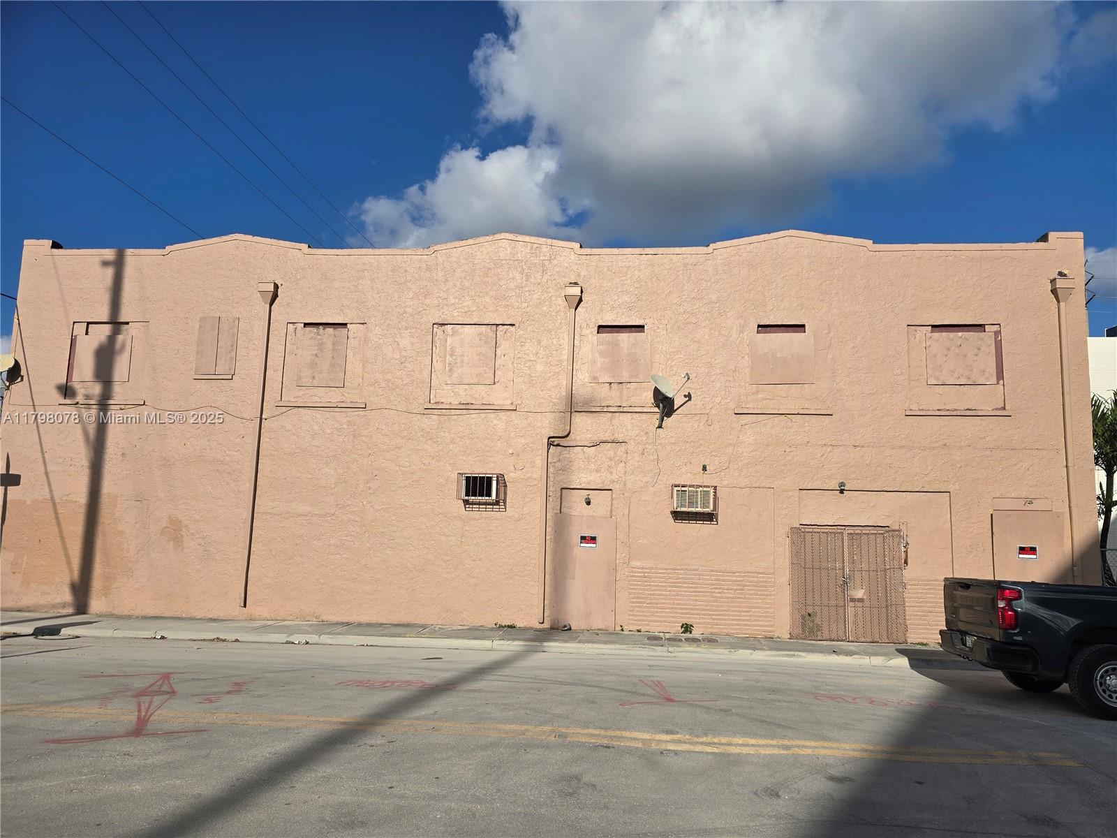 A two-story, peach-colored commercial building features multiple boarded-up windows and a metal security gate — 130 NW 14th St, Miami FL 33136, MIAMI, FL