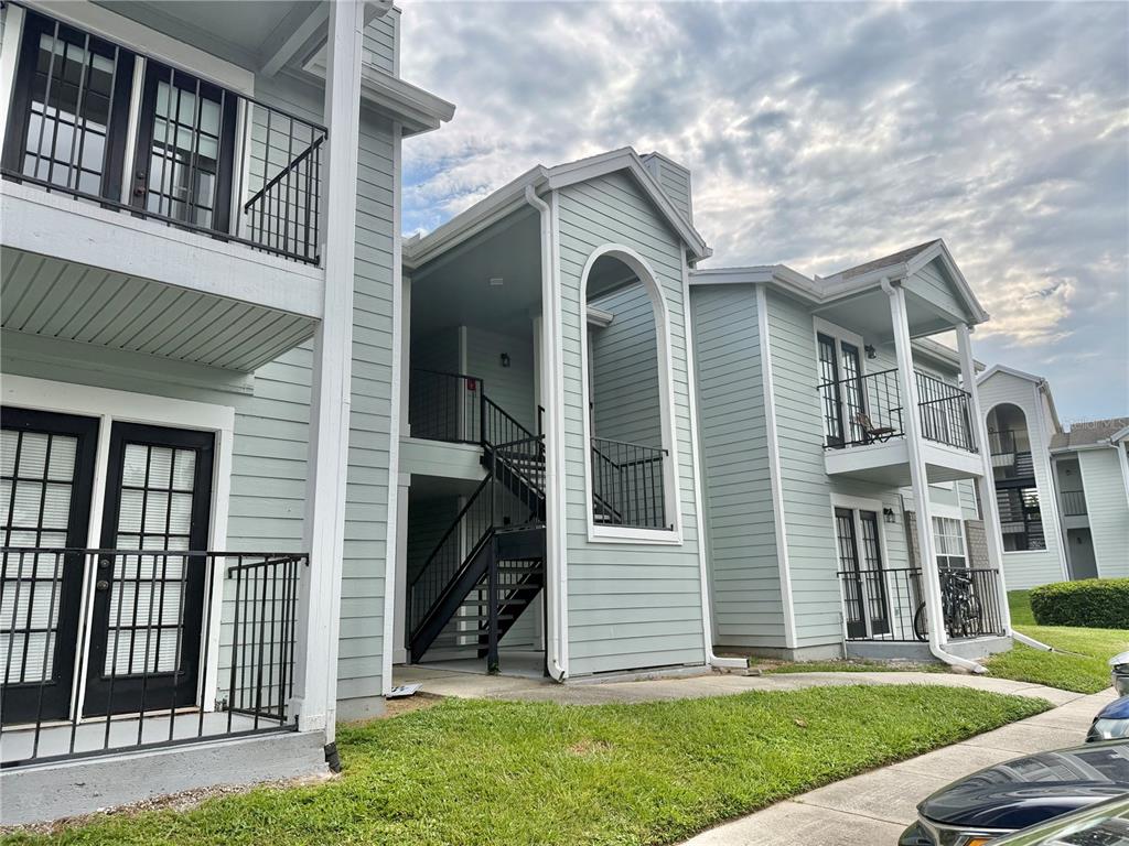 Exterior view of a multi-story apartment building with light green siding and black metal railings — 2550 N ALAFAYA TRAIL UNIT 5103, ORLANDO, FL
