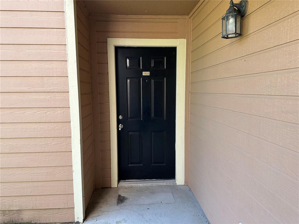 A black front door with the number 5103 is set into tan horizontal siding — 2550 N ALAFAYA TRAIL UNIT 5103, ORLANDO, FL