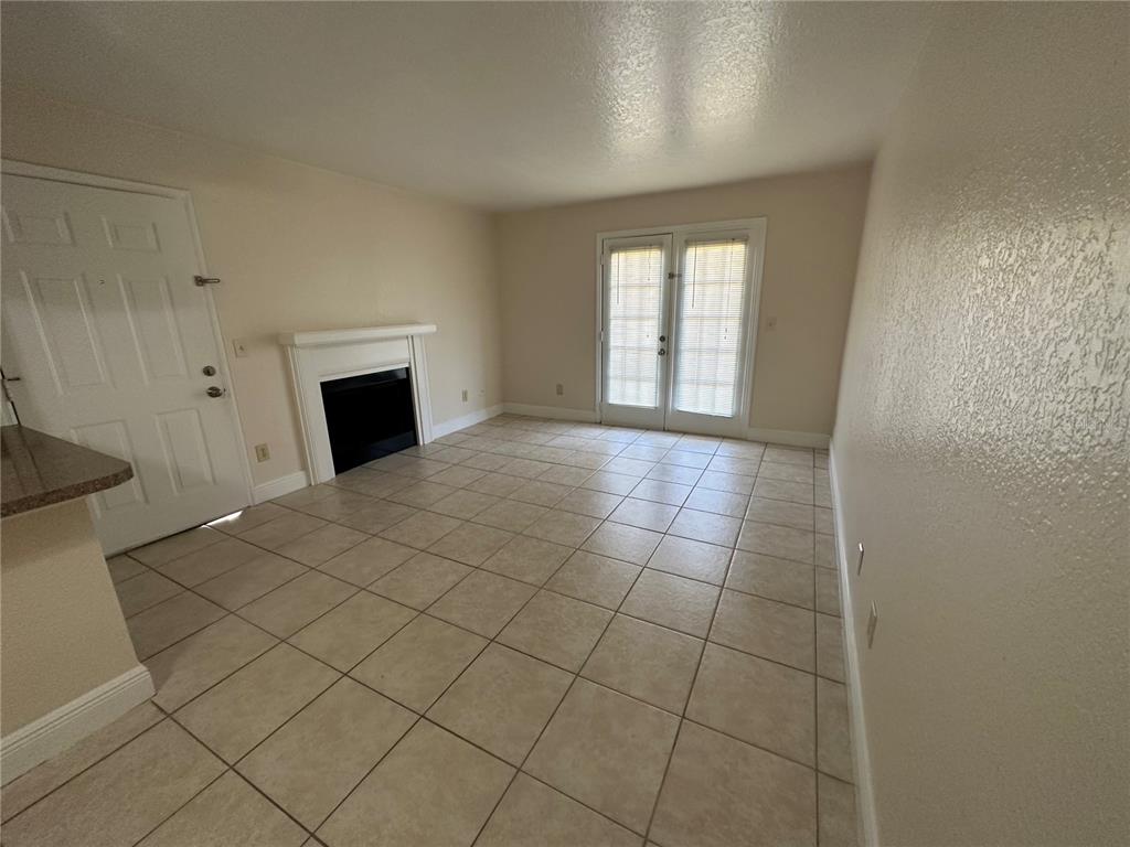 A living room with tile flooring, a fireplace, and glass doors leading to the outside — 2550 N ALAFAYA TRAIL UNIT 5103, ORLANDO, FL