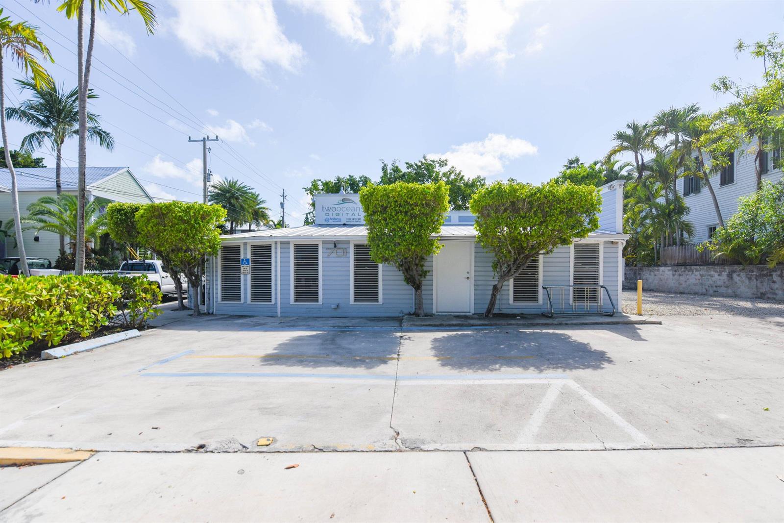A light blue single-story commercial building with a parking lot and two trimmed trees — 701 Simonton Street, Key West FL 33040, KEY WEST, FL