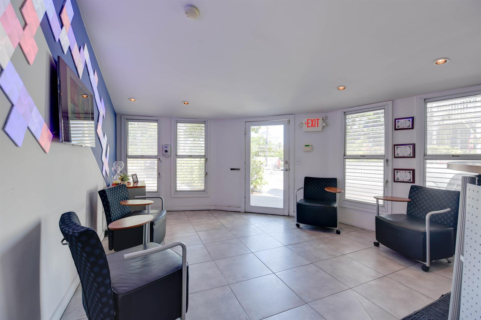 A waiting room features tiled floors, four dark chairs with side tables, and wall-mounted lighting — 701 Simonton Street, Key West FL 33040, KEY WEST, FL