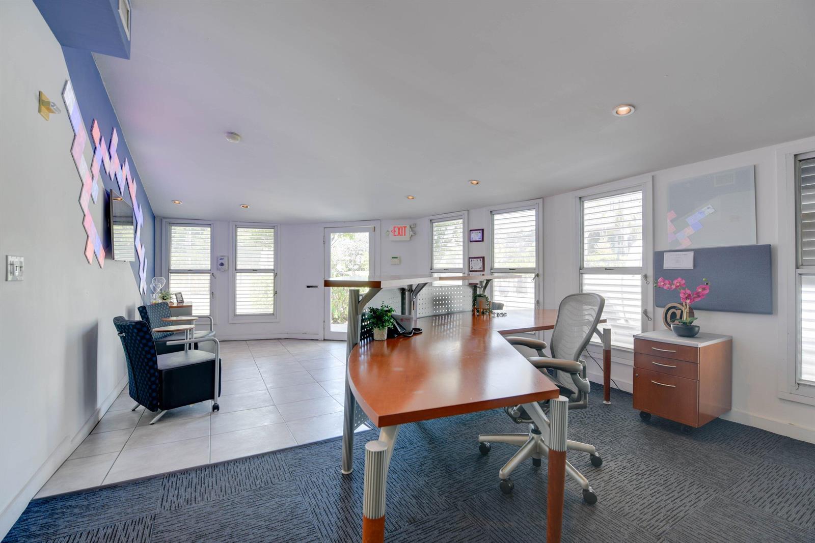 An office space features a large wooden desk, a rolling chair, and a seating area — 701 Simonton Street, Key West FL 33040, KEY WEST, FL