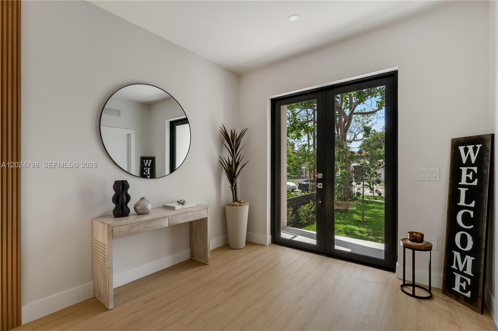 An entryway features a console table, round mirror, potted plant, and glass double doors — 1917 NW 17 ST # A, Miami FL 33125, MIAMI, FL