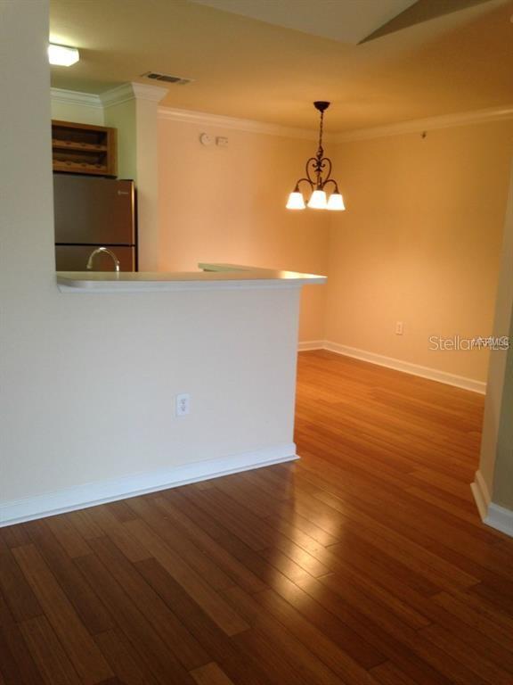 A kitchen with a breakfast bar overlooks a dining area featuring hardwood floors and lighting — 18147 STERLING GATE CIRCLE UNIT 18147, TAMPA, FL