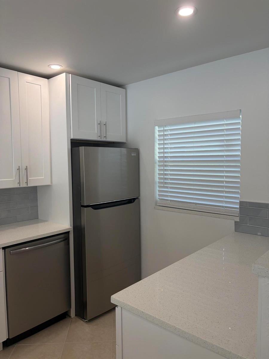 A kitchen features white cabinets, stainless steel appliances, a quartz countertop, and a window — 2900 Fiore Way # 2110, Delray Beach FL 33445, DELRAY BEACH, FL