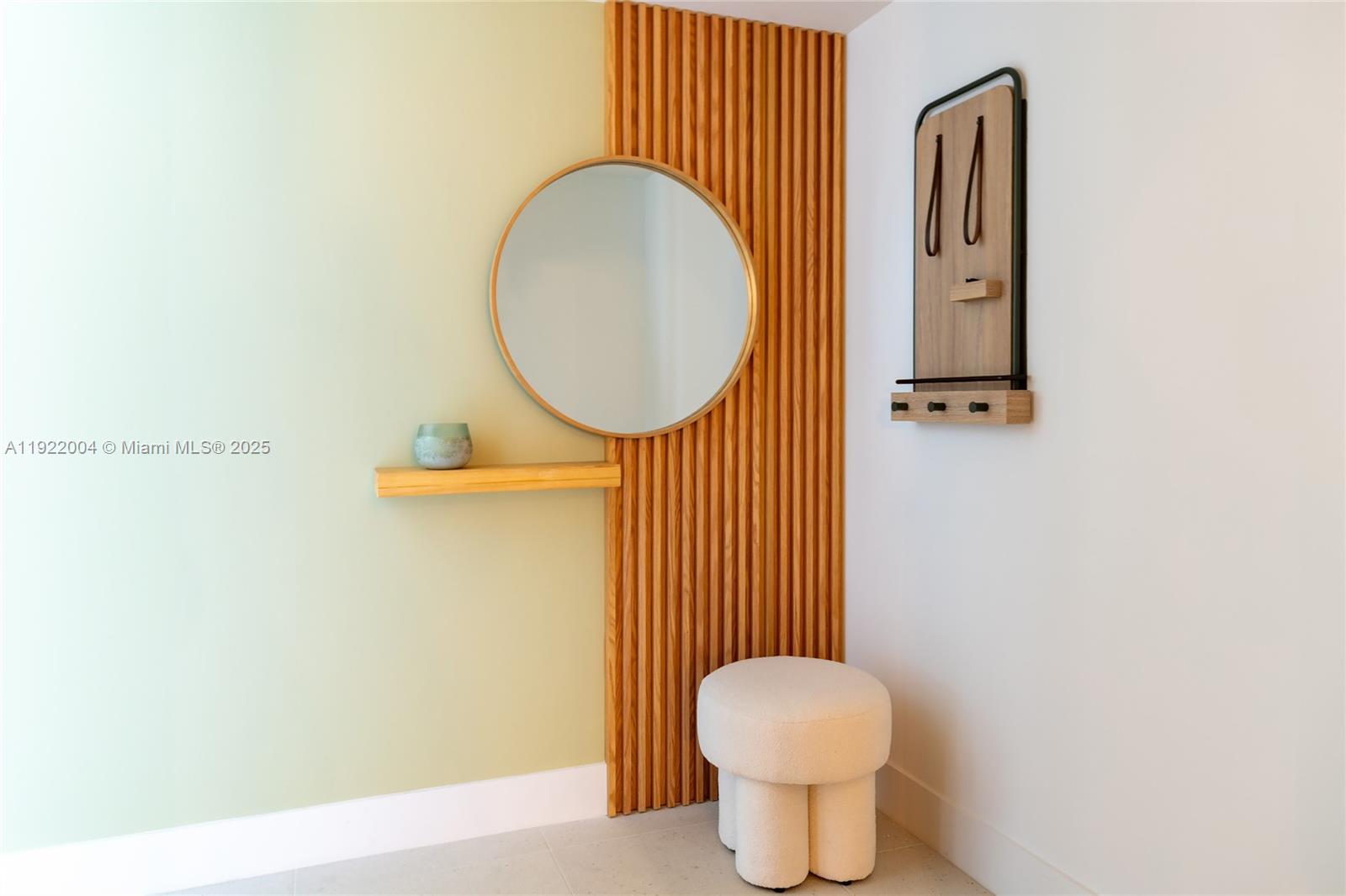 A modern entryway features a round mirror, wooden slat wall, floating shelf, and white stool — 159 NE 6th St # 3002, Miami FL 33132, MIAMI, FL