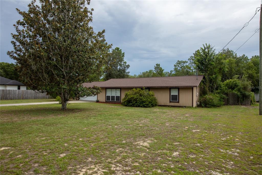 A single-story house with brown siding and a shingled roof sits on a grassy lot — 692 SE 41ST STREET, KEYSTONE HEIGHTS, FL