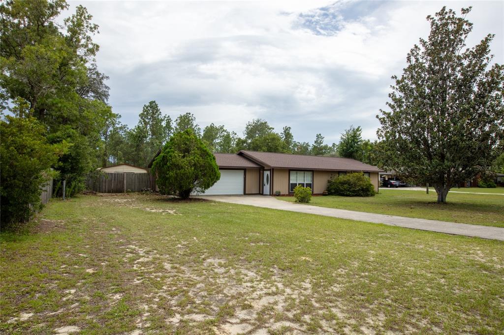 A single-story house with a brown roof, beige siding, and a concrete driveway — 692 SE 41ST STREET, KEYSTONE HEIGHTS, FL