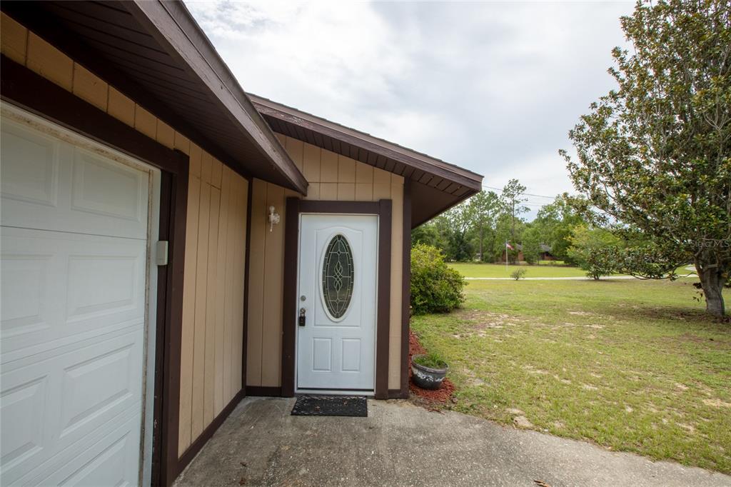 An exterior view of a house entrance with a white door and a garage door — 692 SE 41ST STREET, KEYSTONE HEIGHTS, FL