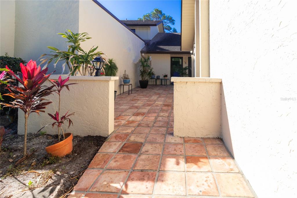 A tiled walkway leads to the entrance of a house with stucco walls — 4660 LA JOLLA DRIVE, BRADENTON, FL