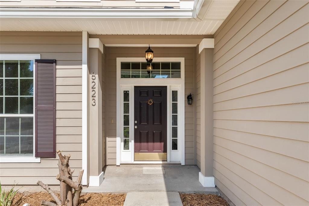 The front exterior of a house features a dark door, sidelights, and a transom window — 8223 NW 53RD STREET, GAINESVILLE, FL