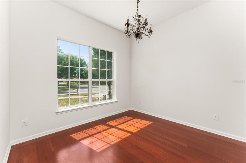 A dining room with hardwood floors, a chandelier, and a large window overlooking a street — 8223 NW 53RD STREET, GAINESVILLE, FL