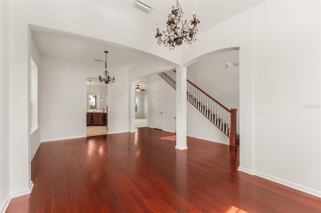 A dining area with hardwood floors, a chandelier, and an open view of a staircase — 8223 NW 53RD STREET, GAINESVILLE, FL