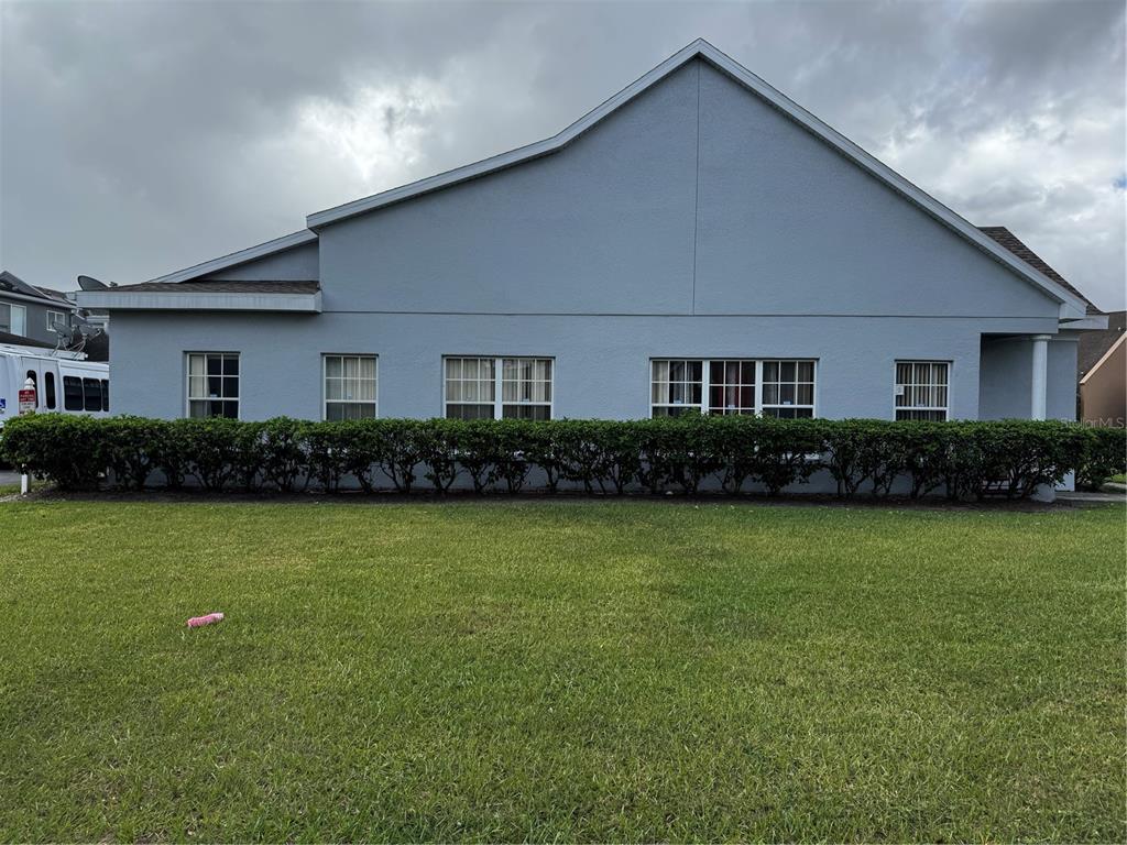 A light blue exterior wall of a house features five windows above a trimmed hedge — 2082 ISLAND WALK DRIVE, ORLANDO, FL