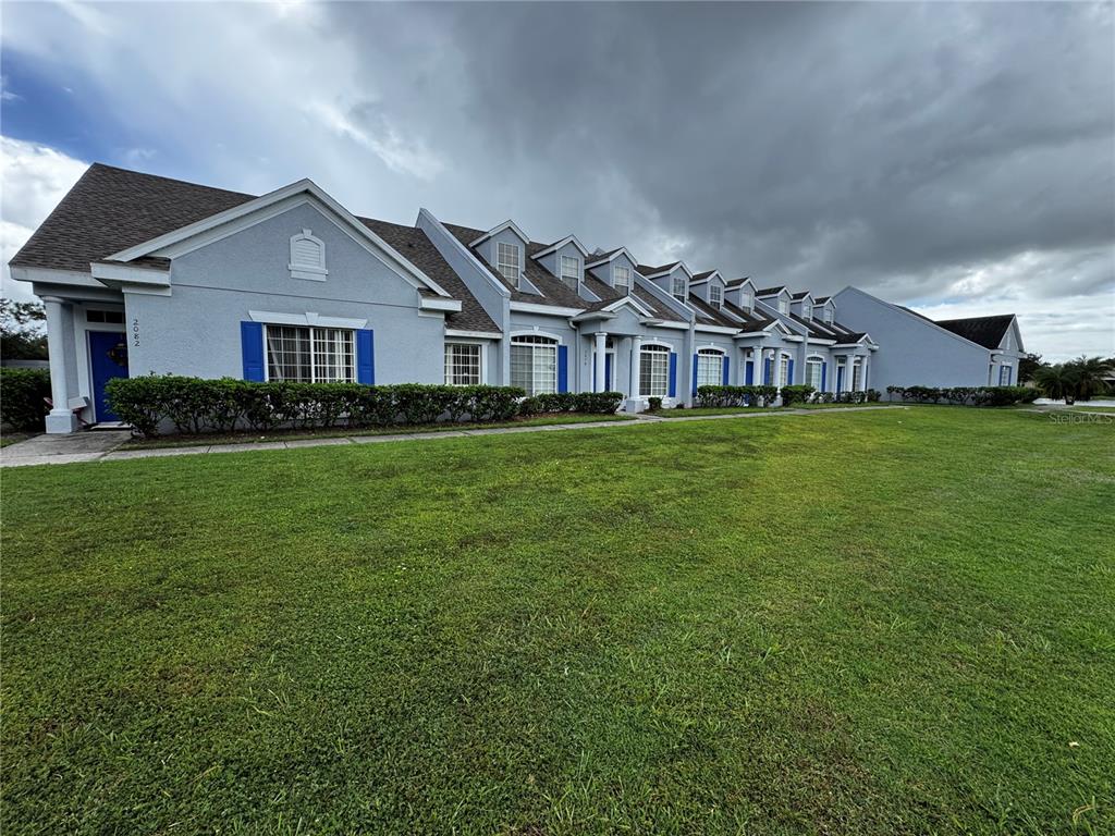 A row of attached townhomes with light blue stucco siding and dark shingled roofs — 2082 ISLAND WALK DRIVE, ORLANDO, FL