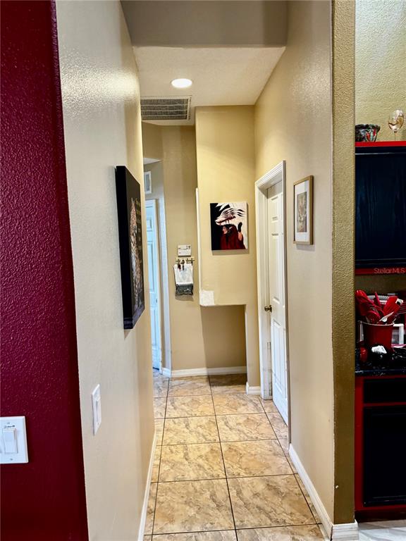 A hallway with tan walls, tile flooring, and several pieces of wall art — 2082 ISLAND WALK DRIVE, ORLANDO, FL