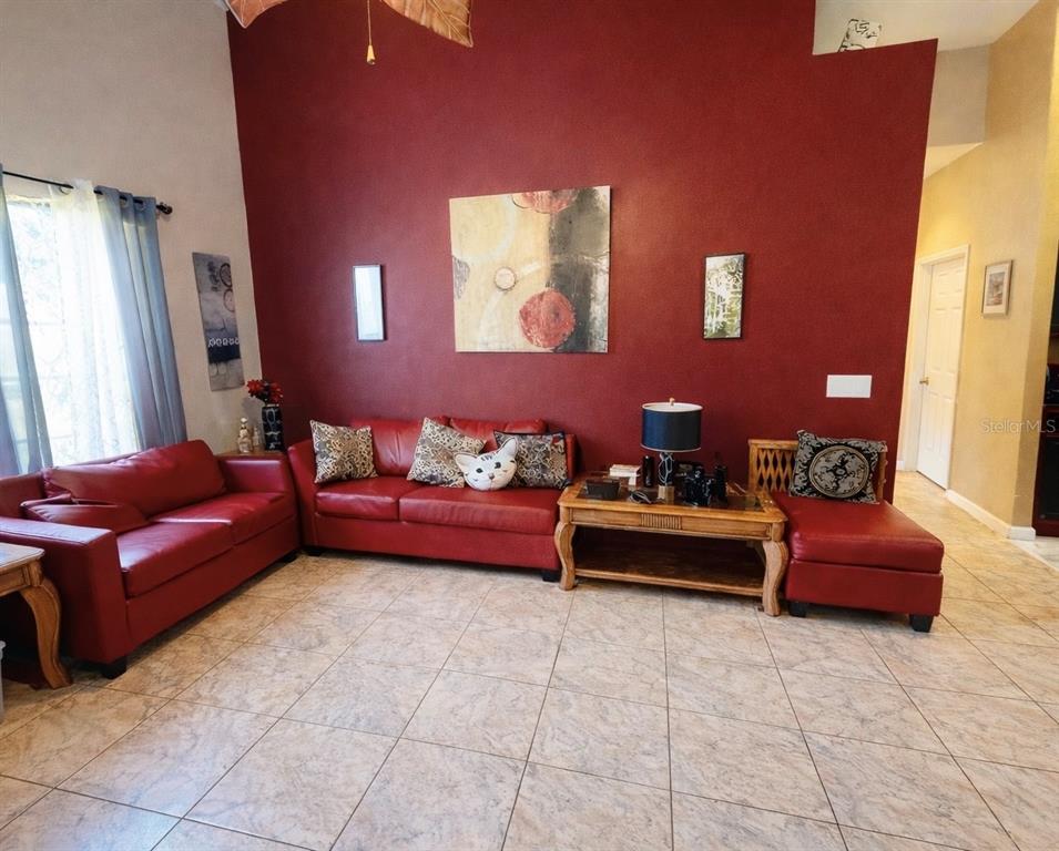 A living room features red leather sofas, a wooden coffee table, and a red accent wall — 2082 ISLAND WALK DRIVE, ORLANDO, FL