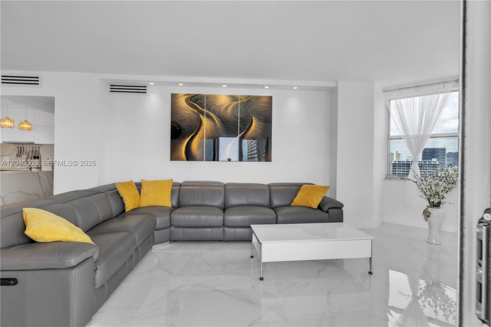 A living room features a grey sectional sofa, yellow pillows, and a white coffee table — 1965 S Ocean Dr, Hallandale Beach FL 33009, HALLANDALE BEACH, FL