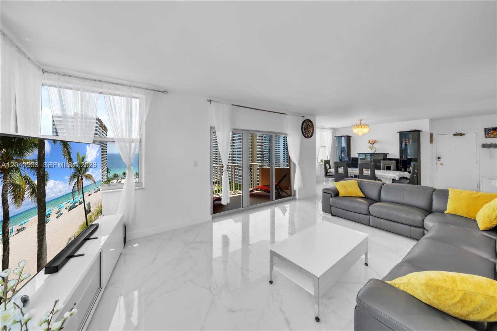 A bright living room features white marble floors, a grey sectional sofa, and balcony access — 1965 S Ocean Dr, Hallandale Beach FL 33009, HALLANDALE BEACH, FL