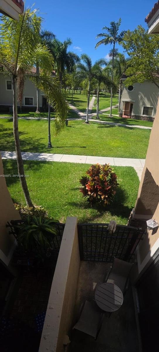 A view from a balcony overlooking a grassy courtyard with palm trees and walkways — 22911 SW 88th Pl # 21, Cutler Bay FL 33190, CUTLER BAY, FL
