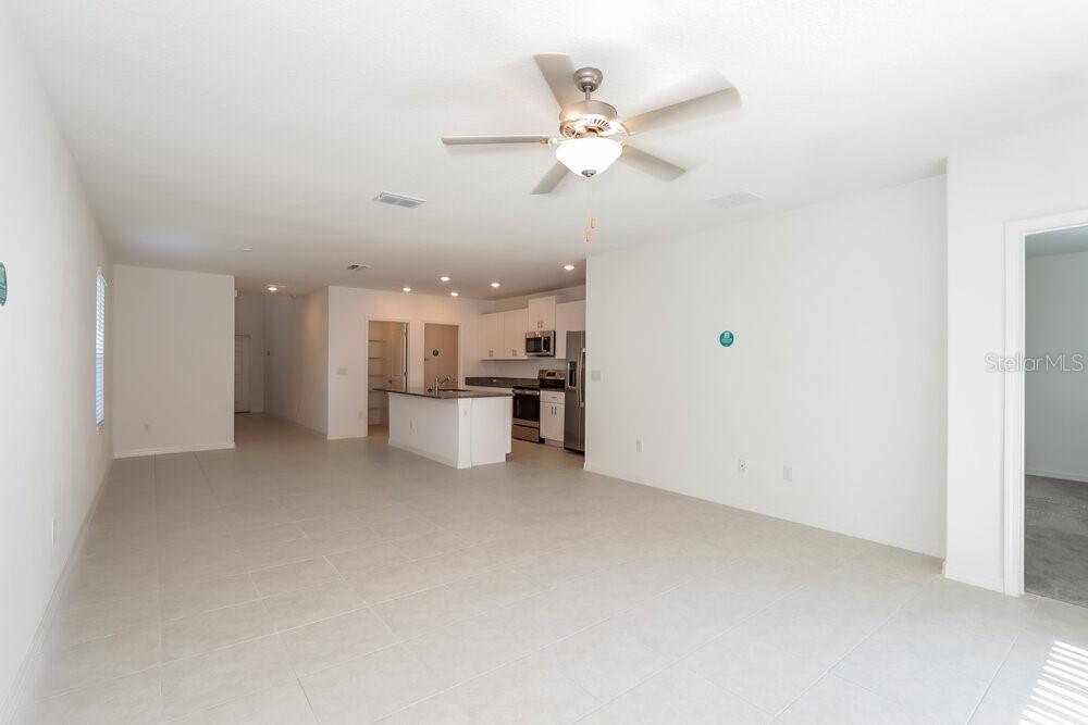 An open-concept living area features light tile flooring, a ceiling fan, and a kitchen island — 17994 BLISSFUL STARS DRIVE, LUTZ, FL